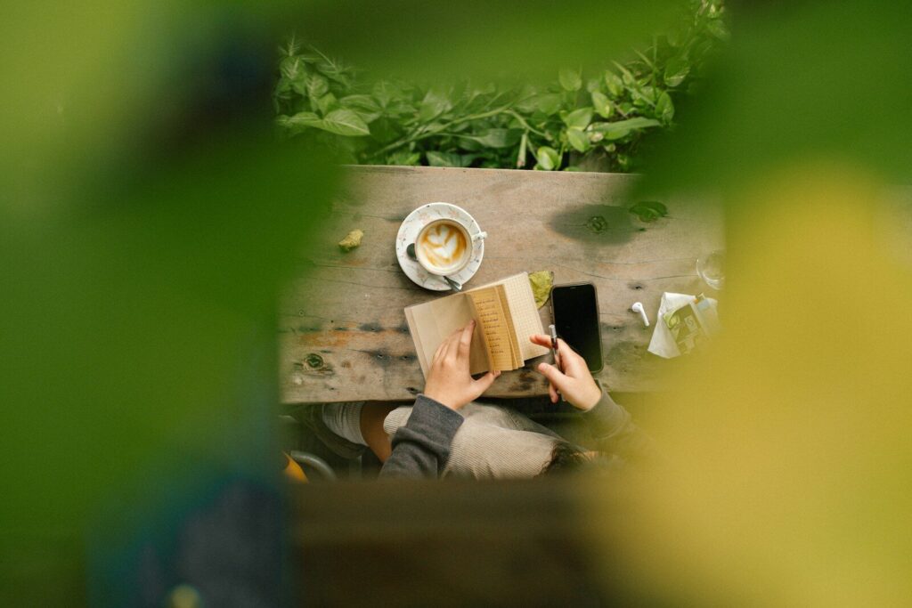 Person reading a book with coffee at a table.
