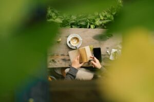 Person reading a book with coffee at a table.